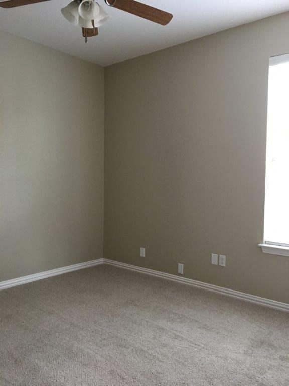 an empty living room with a ceiling fan
