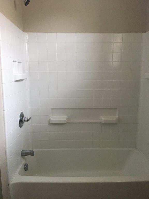 a white bath tub in a white tiled bathroom