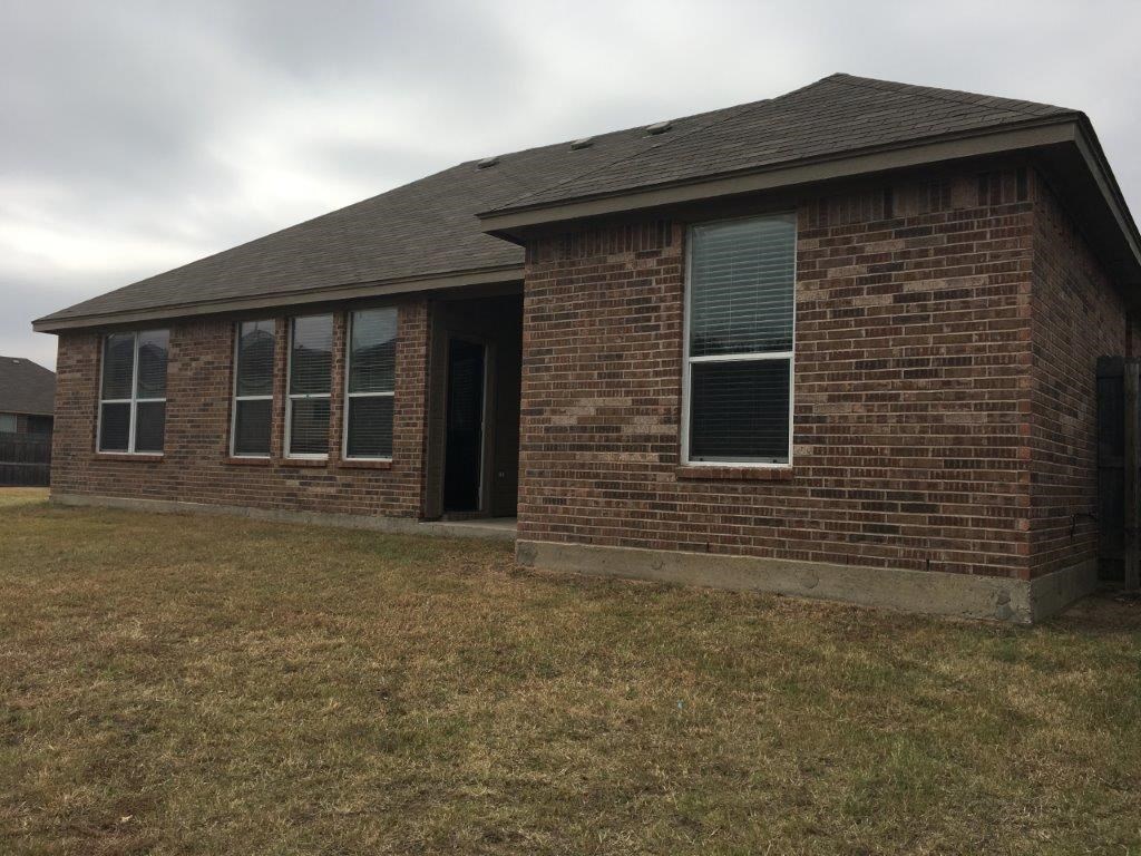 a small brick house with the front door open