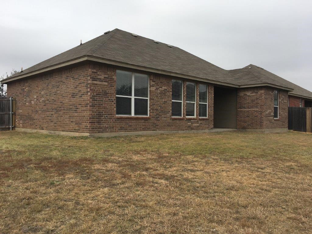 a small brick house with a yard in front of it