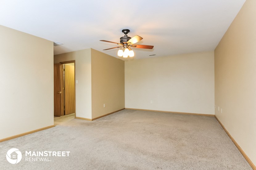 the living room of an empty house with a ceiling fan