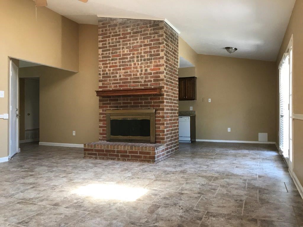 an empty living room with a brick fireplace