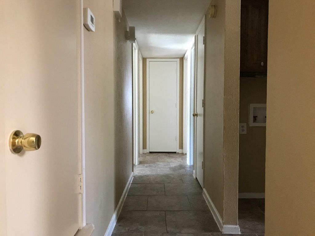 a hallway with white walls and a door with a gold door knob