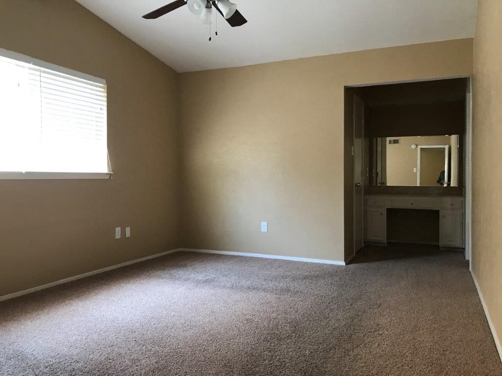 an empty room with a ceiling fan and a window