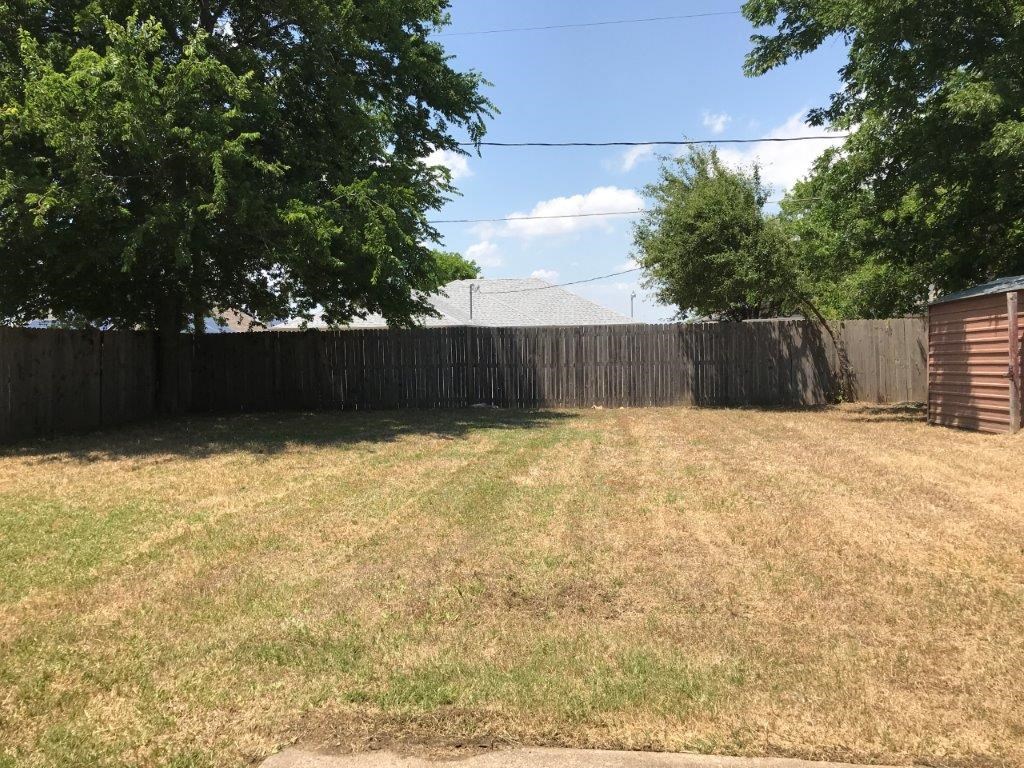 a backyard with a fence and some grass and trees