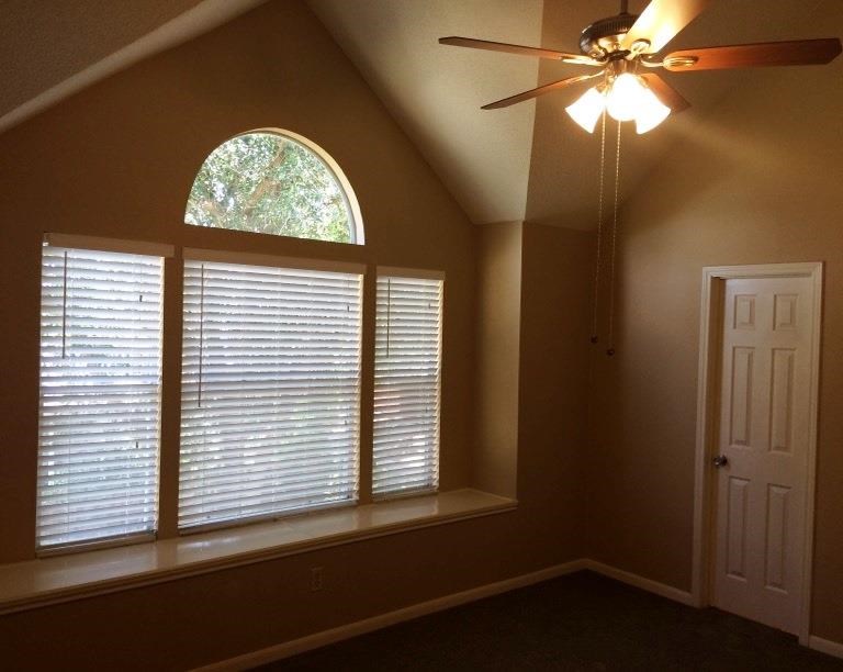 a living room with a large window and a ceiling fan