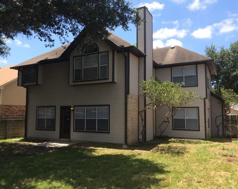 a tan house with a yard and a tree