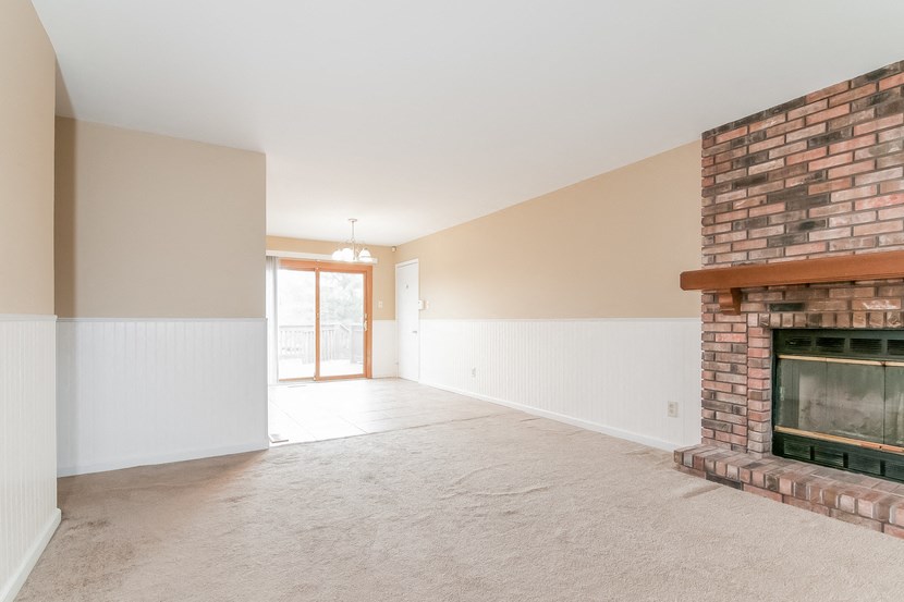 an empty living room with a brick fireplace and white walls