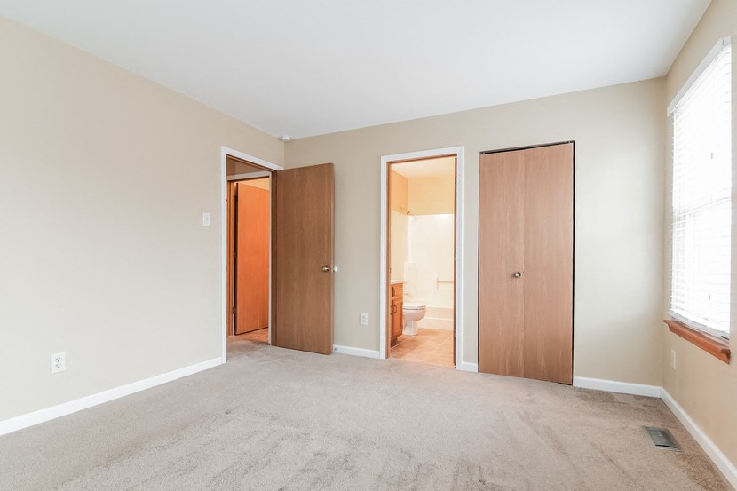 an empty living room with doors to a bedroom and a bathroom