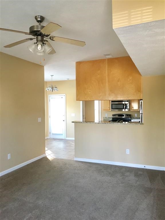 an empty living room and kitchen with a ceiling fan