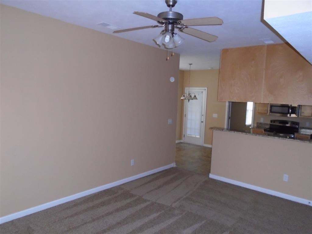 an empty living room with a ceiling fan
