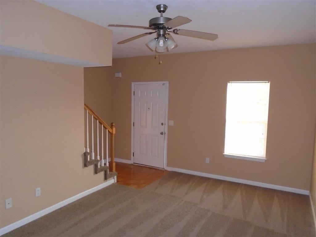 a empty living room with a ceiling fan and a door
