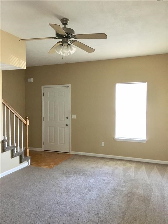 an empty living room with a ceiling fan and a door