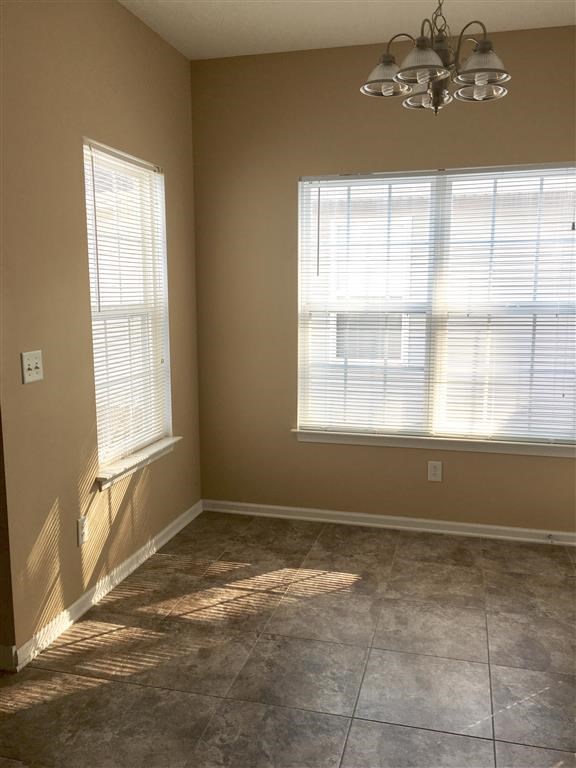 an empty room with two windows and a chandelier