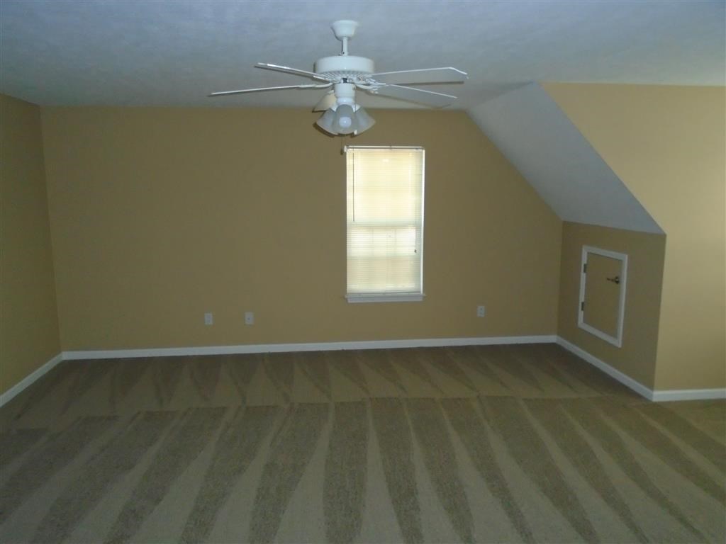 an empty room with a ceiling fan and a window
