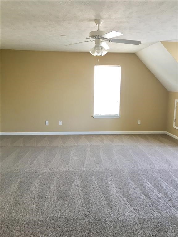 an empty room with a ceiling fan and a window