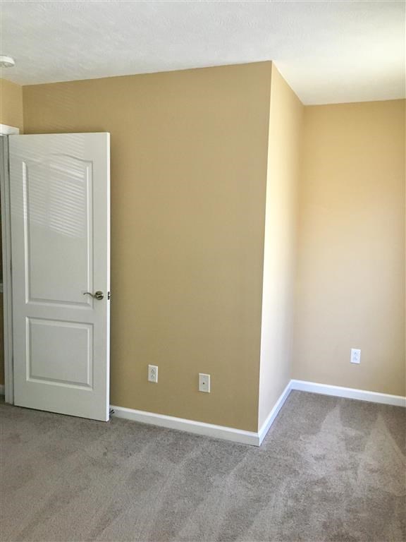 an empty room with a white door and tan walls