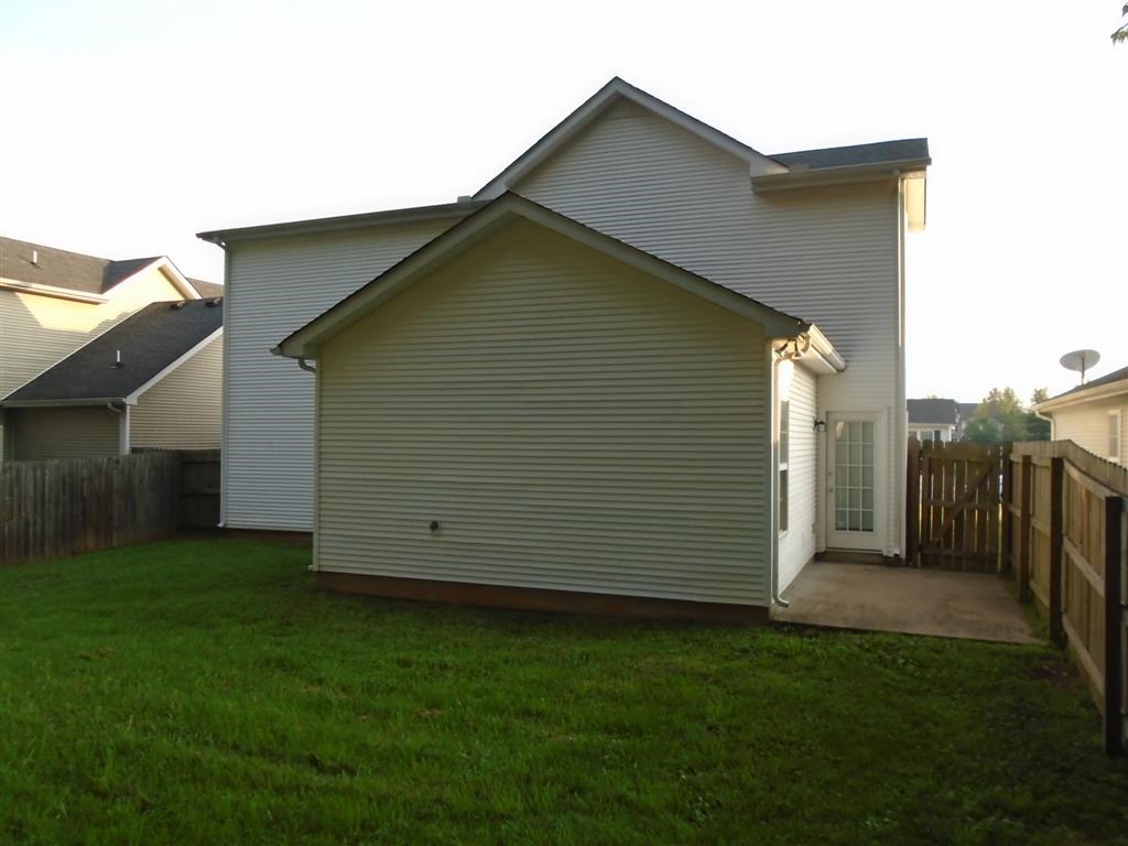 a side view of a house with a yard and a fence
