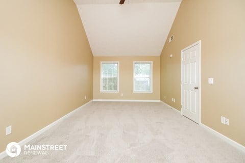 the spacious living room with white carpet and a white door