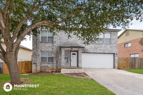 a white brick house with a tree in the front yard