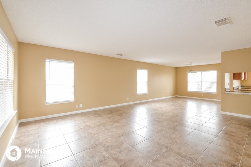an empty living room with tile floors and a large window
