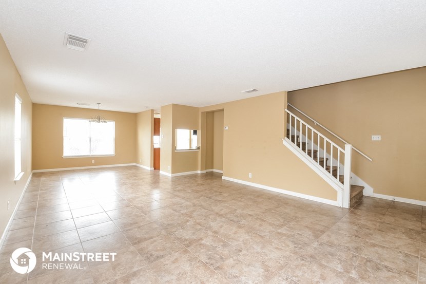 an empty living room with a staircase and a tile floor