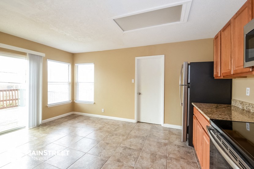 an empty kitchen with a refrigerator and a window