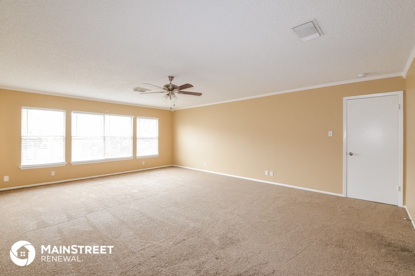 the spacious living room with carpet and a ceiling fan