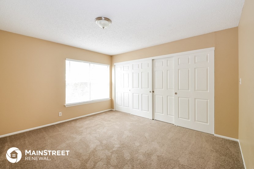 the spacious living room with two closets and a window