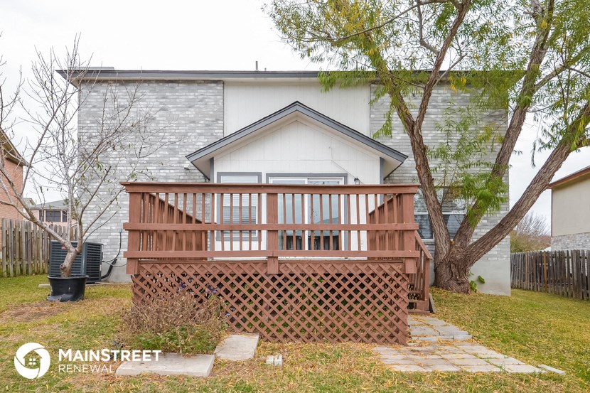 the front of a house with a deck and a tree