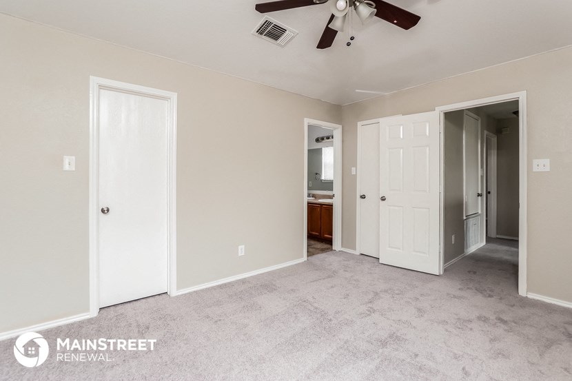a living room with a ceiling fan and a door to a bathroom