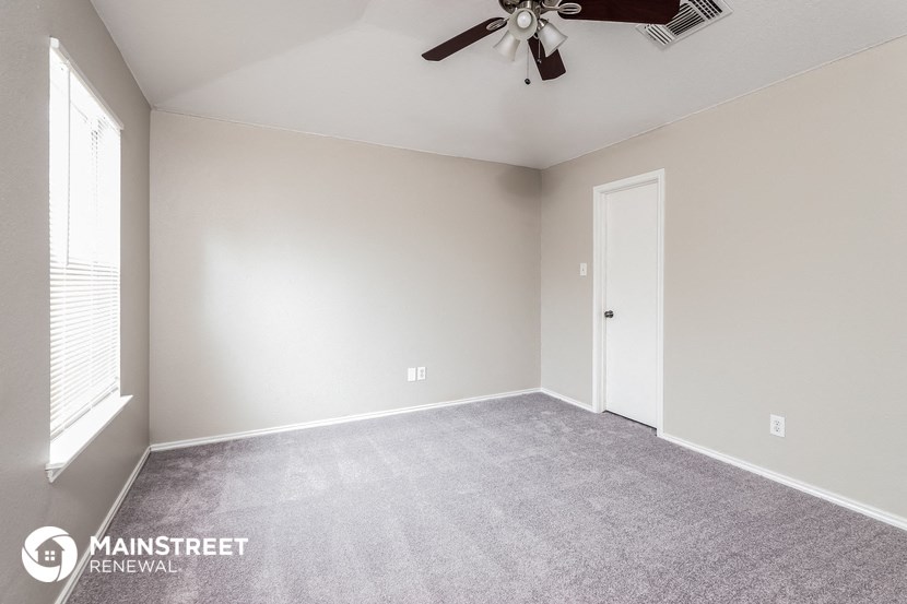the spacious living room with carpet and a ceiling fan