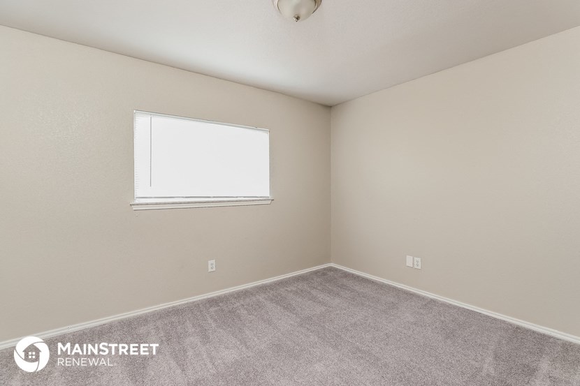 the living room of an apartment with carpet and a window
