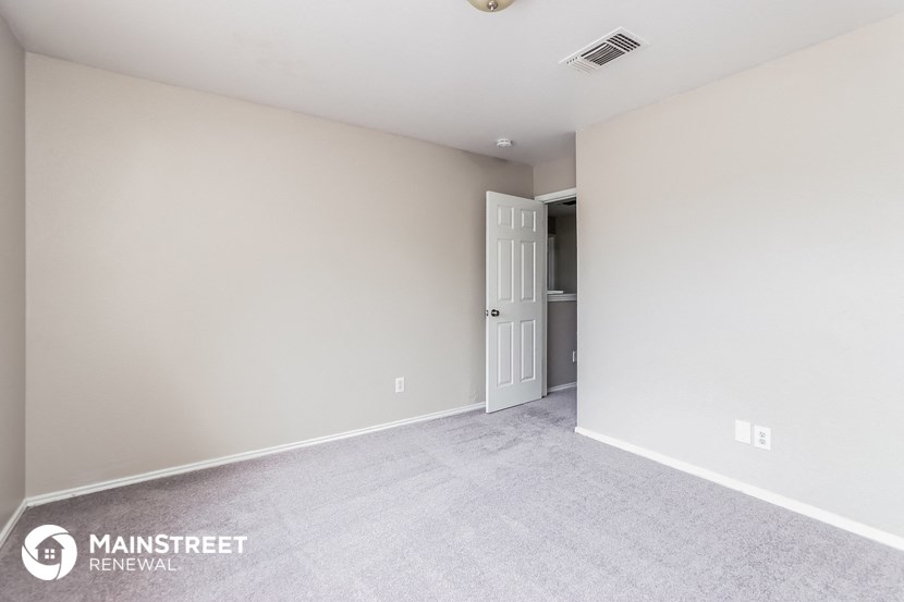 the living room of an apartment with carpet and a door to the bathroom