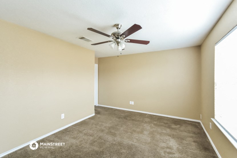 a living room with carpet and a ceiling fan