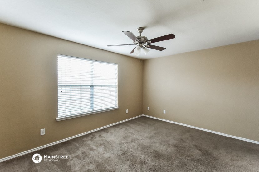 an empty room with a ceiling fan and a window