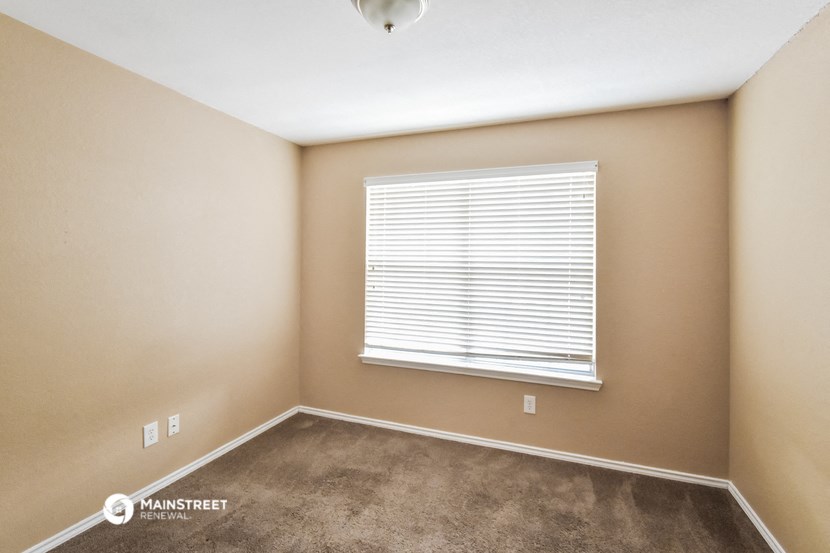 the upstairs bedroom has a large window and carpeted flooring