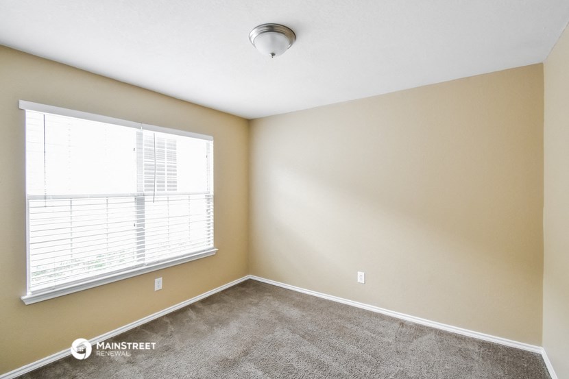 an empty room with a large window and carpet
