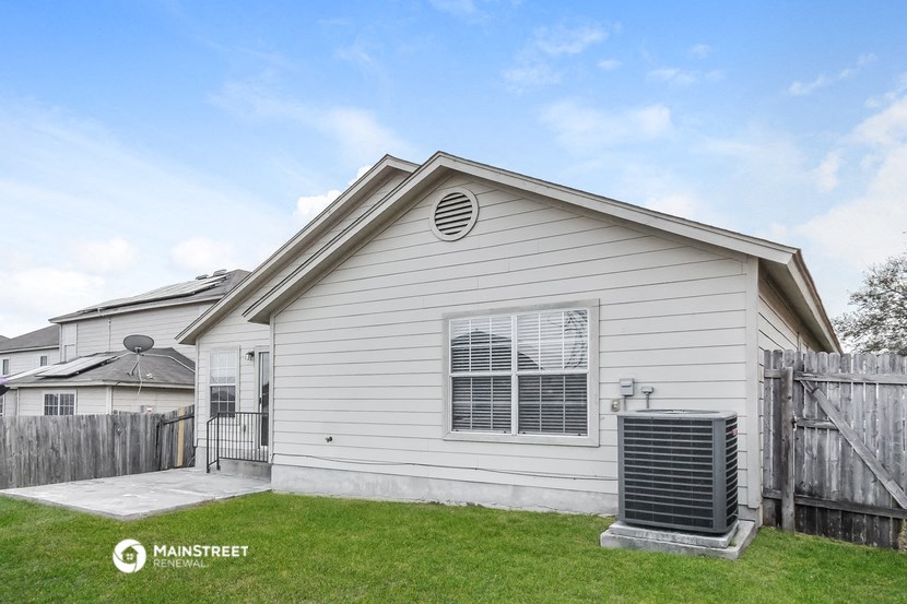the outside of a white house with a yard and a wooden fence
