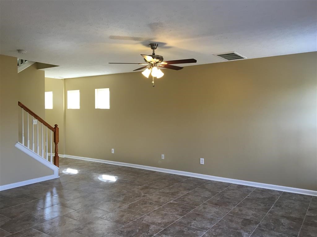 a empty living room with a ceiling fan