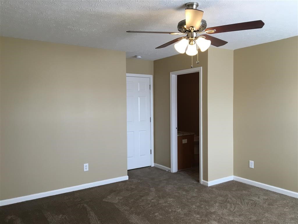 an empty living room with a ceiling fan and a closet