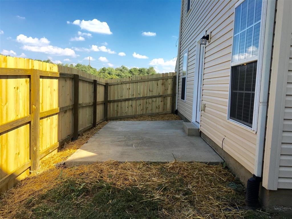 a backyard patio with a fence and a house