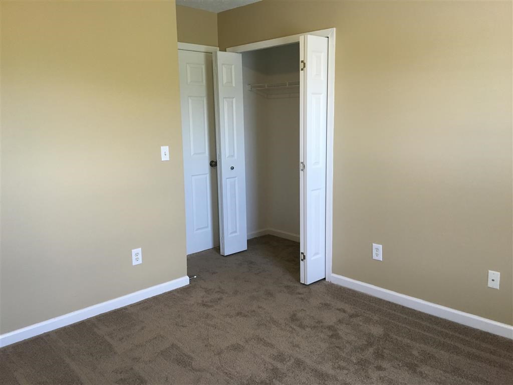 a room with a carpeted floor and a closet and two doors