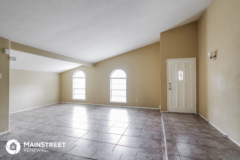 an empty living room with tile floors and a white door