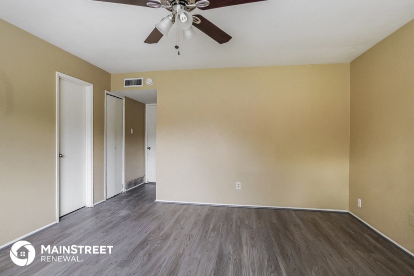 an empty living room with wood floors and a ceiling fan