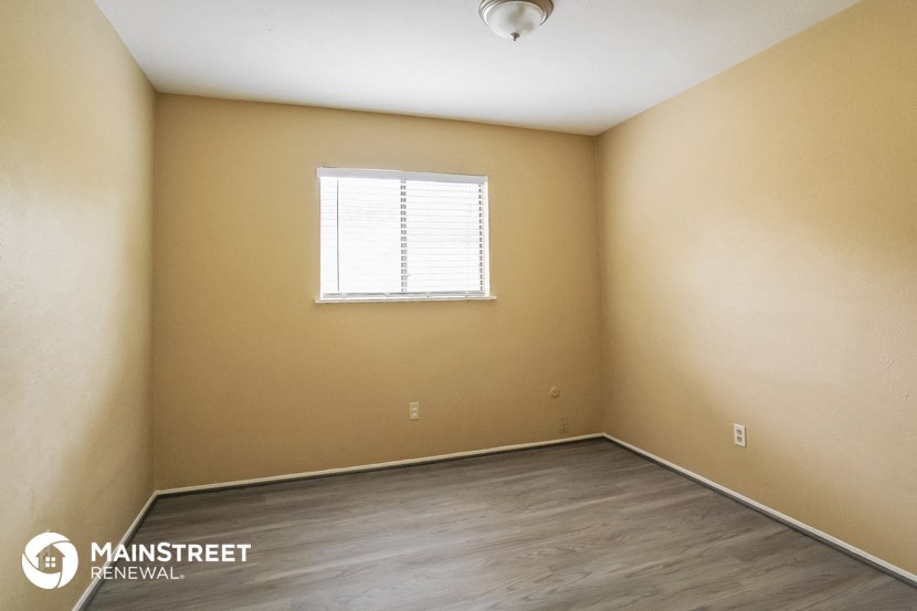 the upstairs bedroom with wood floors and a window