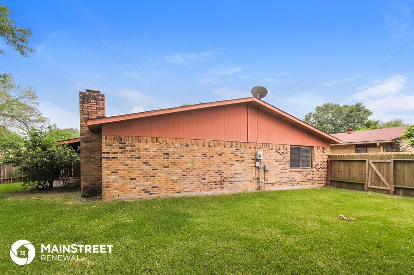 a brick house with a red roof and a green yard