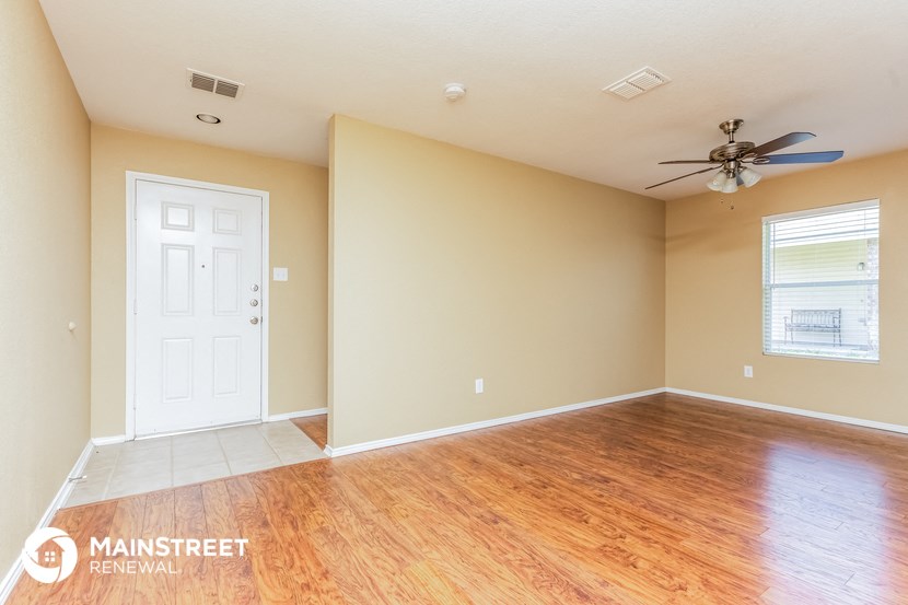 the living room of an empty house with wood floors and a ceiling fan