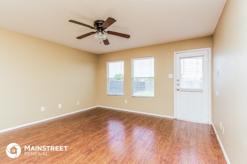a living room with wood floors and a ceiling fan