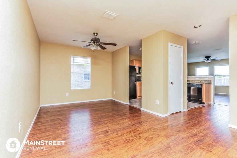 an empty living room with wood floors and a ceiling fan